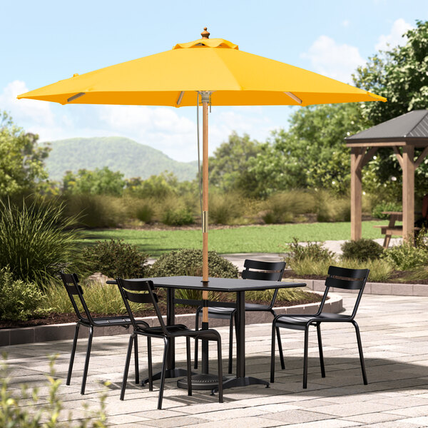 A Lancaster Table & Seating round yellow umbrella on a patio table.