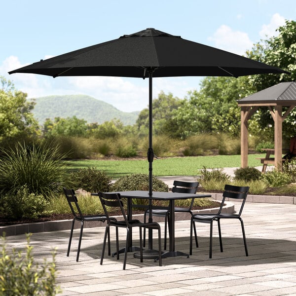 A Lancaster Table & Seating black umbrella over a round patio table with chairs.