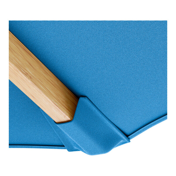 A blue fabric Lancaster Table & Seating umbrella with a wooden pulley lift.