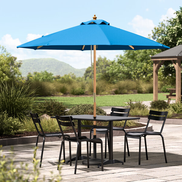 A Lancaster Table & Seating blue umbrella on a patio table.