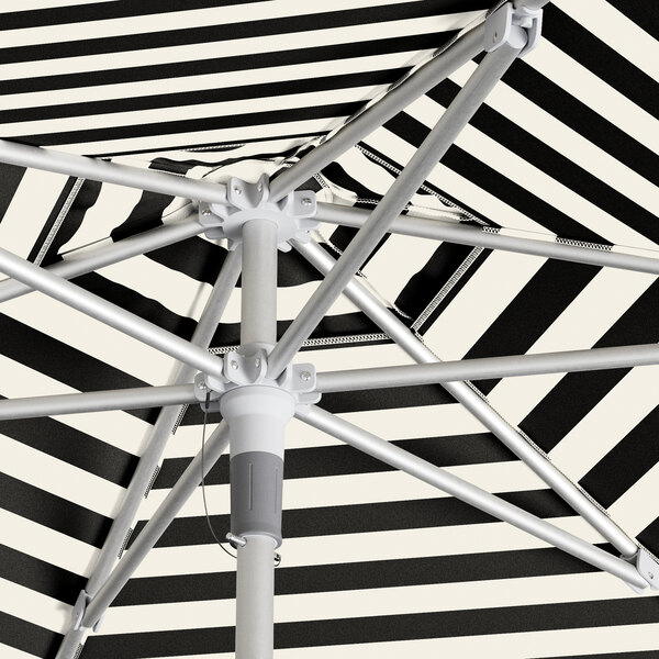 A close up of a Lancaster Table & Seating black and white striped umbrella with a white pole.