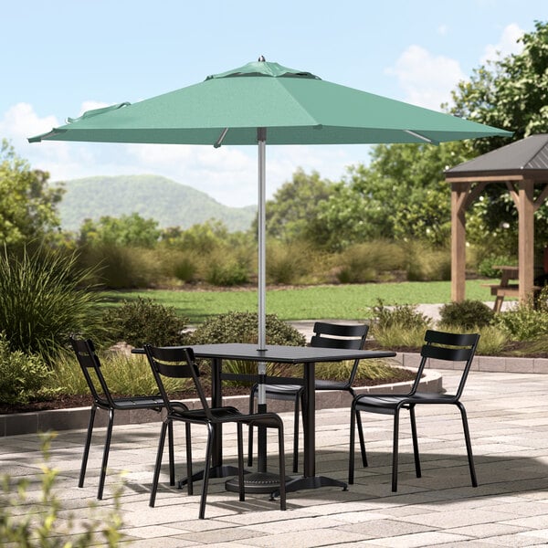 A Lancaster Table & Seating round silver umbrella on a patio table with chairs.