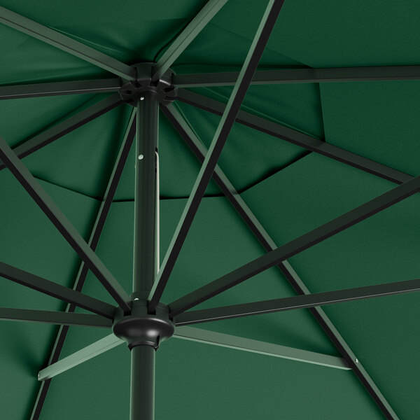 A Lancaster Table & Seating forest green umbrella with black metal poles.