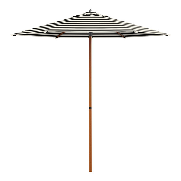 A Lancaster Table & Seating black and white striped umbrella with woodgrain pole.