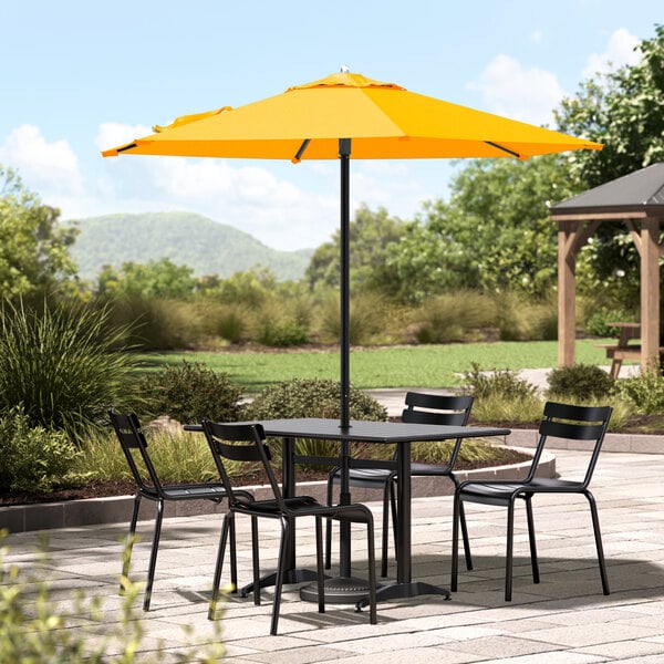 A Lancaster Table & Seating yellow umbrella on a patio table.