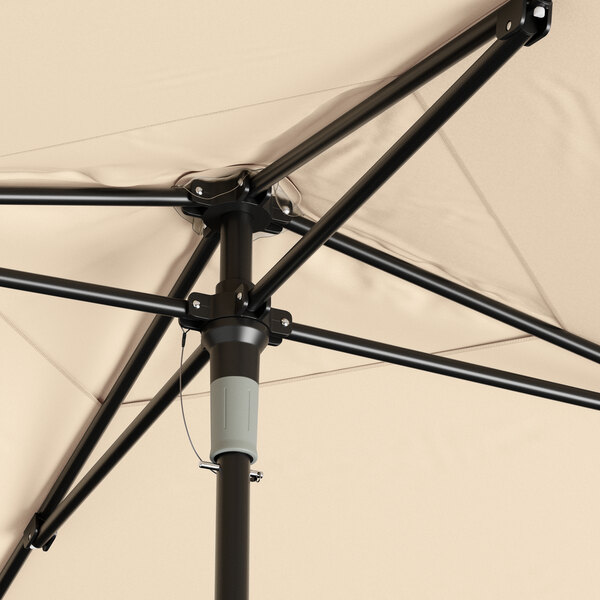A close up of a Lancaster Table & Seating black aluminum umbrella with a black pole.