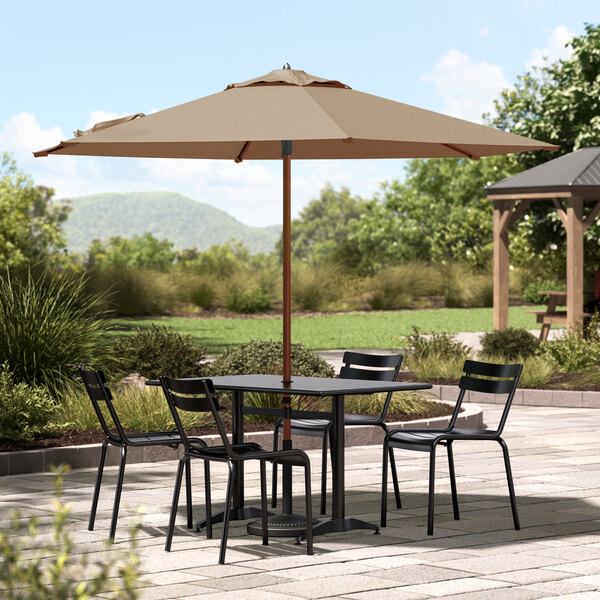 A Lancaster Table & Seating woodgrain umbrella over a round patio table with chairs.