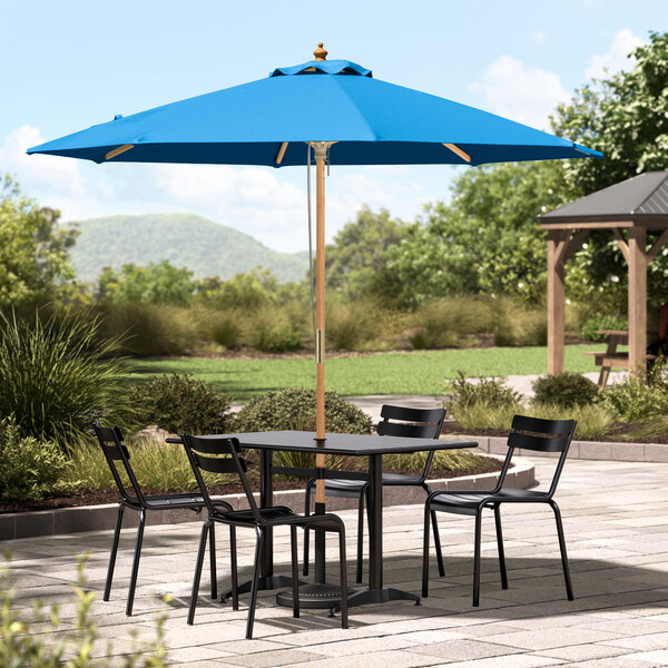 A blue Lancaster Table & Seating umbrella on a patio table.