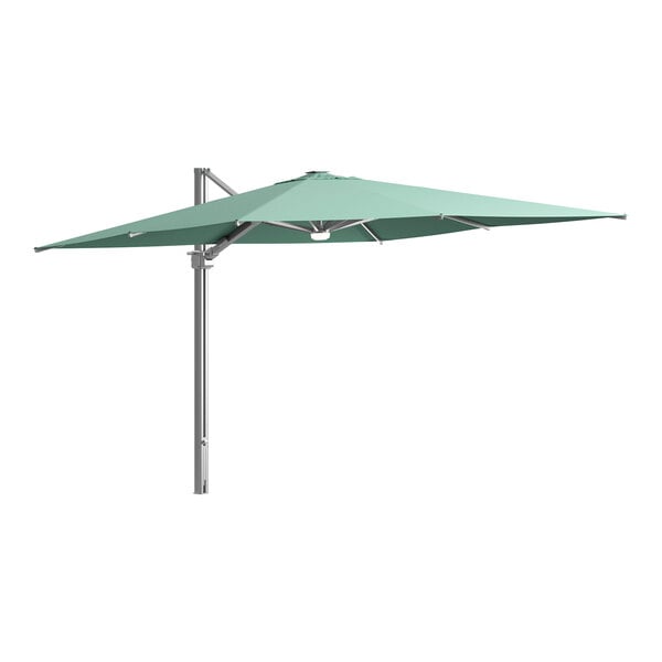 A large green Lancaster Table & Seating cantilever umbrella with lights on a metal pole.