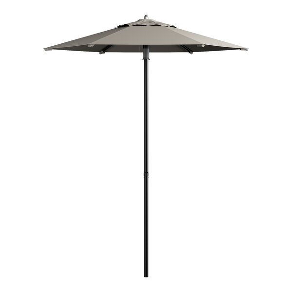 A Lancaster Table & Seating graphite umbrella on a pole over a white table.