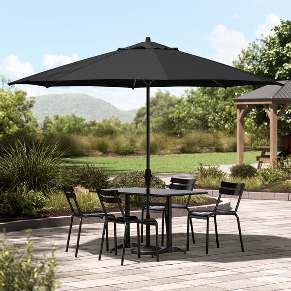 A black table and chairs under a Lancaster Table & Seating black umbrella on a patio.