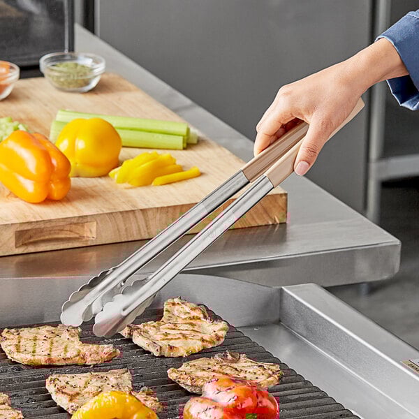 A person using Vollrath stainless steel tongs to grill vegetables.