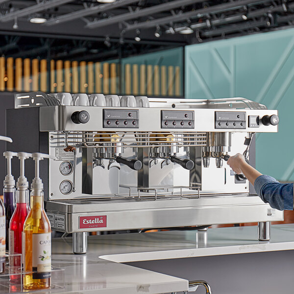 A person using an Estella Caffe Teapresso Machine on a counter in a café.