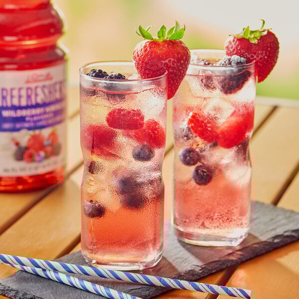 Two glasses of Dr. Smoothie Wildberry Hibiscus refresher with ice and fruit.