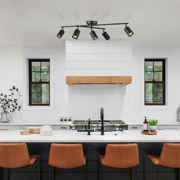 A kitchen with a Globe 5-light matte black track light above a bar and chairs.