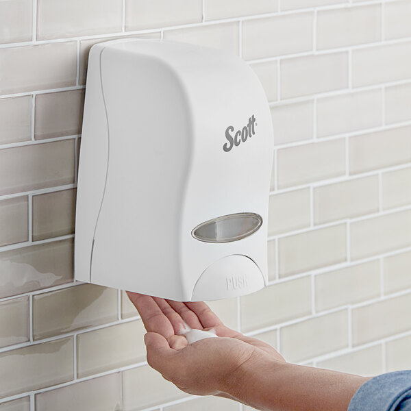 A person using a white Scott Essential manual liquid soap dispenser.