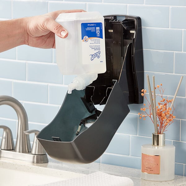 A hand pouring Scott antimicrobial foaming hand soap into a dispenser.