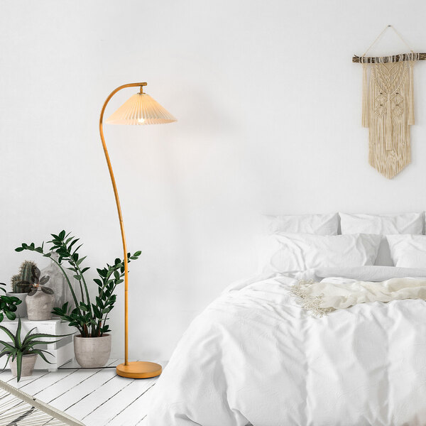 A white bedroom with a Globe Novogratz Bohemian wood-toned floor lamp next to a white bed.