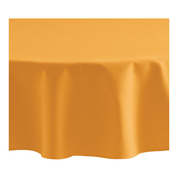 A round orange tablecloth on a table with a yellow background.