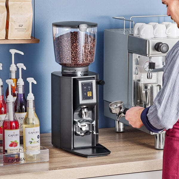 A man using an Anfim On-Demand Espresso Grinder at a coffee machine.