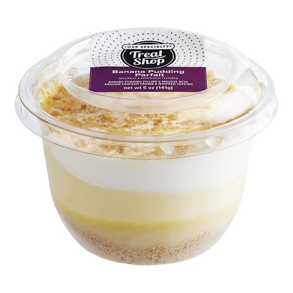 A plastic container of Our Specialty Treat Shop Banana Pudding with a white and yellow dessert inside.