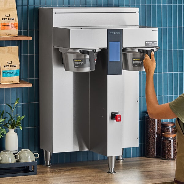 A woman using a Fetco CBS-2252 coffee maker.
