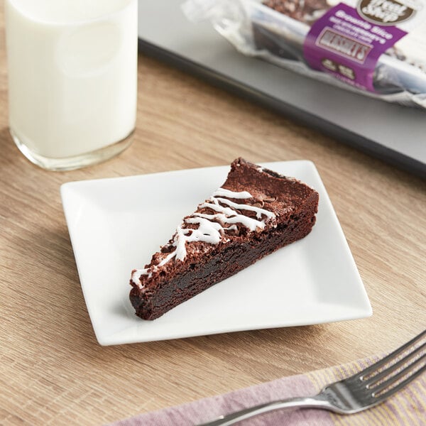 An individually wrapped HERSHEY'S chocolate chip brownie slice on a plate with a fork next to a glass of milk.