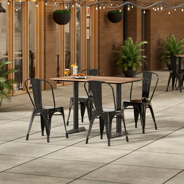 A Lancaster Table and Seating rectangular wooden table with black chairs on a patio.