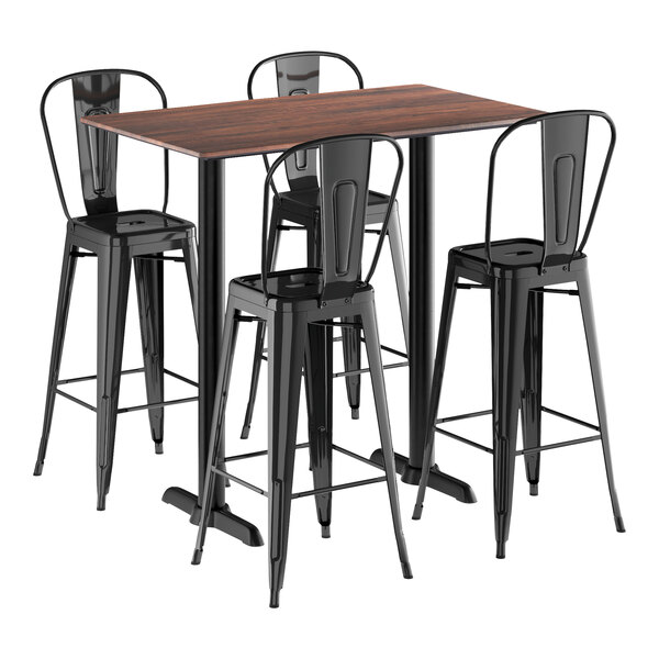 A Lancaster Table & Seating rectangular walnut bar height table with black metal legs and three black bar stools.