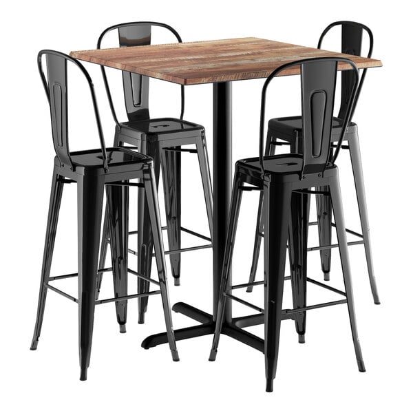 A Lancaster Table & Seating Excalibur bar height table with a textured wood top and four black metal barstools with black backs.