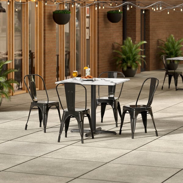 A Lancaster Table & Seating Versilla table and chairs on an outdoor patio.