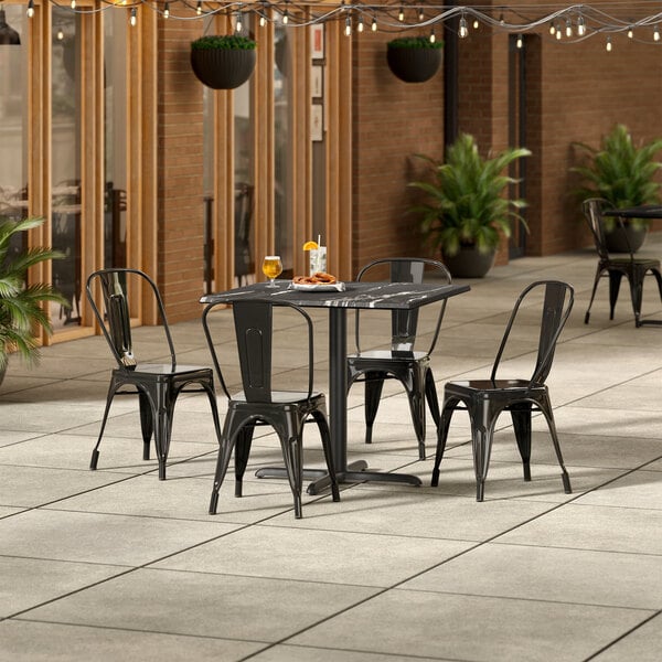 A Lancaster Table & Seating Excalibur table and chairs on an outdoor patio.