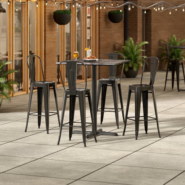 A Lancaster Table & Seating Paladina bar height table with 4 chairs on a patio.