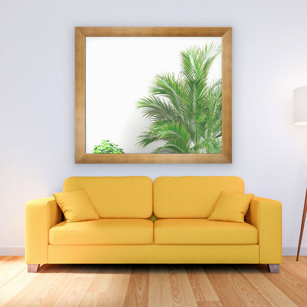 A yellow couch in front of a BrandtWorks brushed gold finish mirror with a lamp on one side and a table on the other.