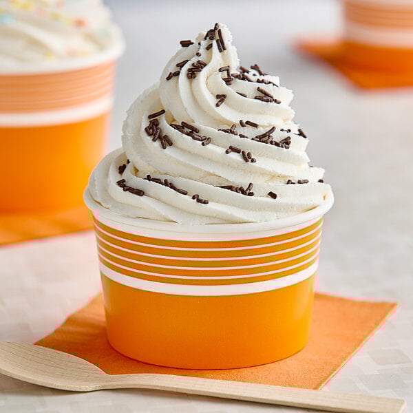 An orange and white paper cup filled with frozen yogurt.
