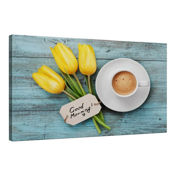 A white canvas print of yellow tulips and a coffee cup on a blue wood table.