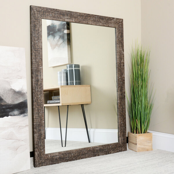 A BrandtWorks Urrutia mirror in a room with a tall green plant in front of it.