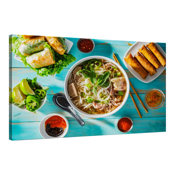 A Vietnamese feast with a bowl of soup, a plate of food, and bowls of sauce on a blue table.