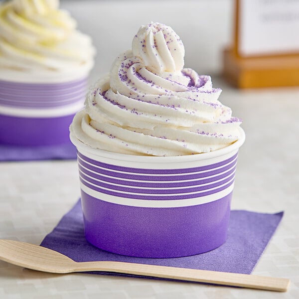 Two purple Choice paper frozen yogurt cups filled with ice cream with a wooden spoon.