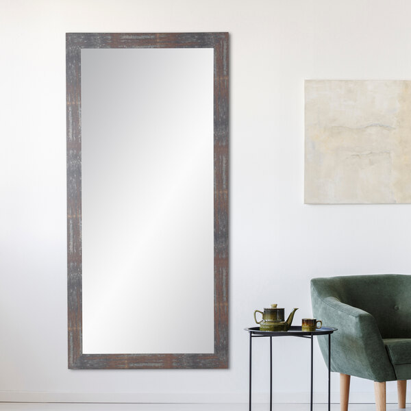 A BrandtWorks Lauralee Rust Finish mirror on a wall above a green chair and small table.