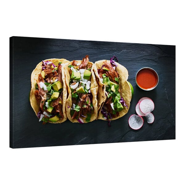 A white canvas with a group of gourmet pork tacos topped with sauce and vegetables.
