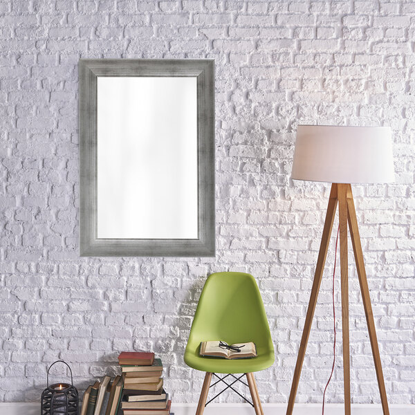 A BrandtWorks vintage silver finish mirror on a white brick wall.