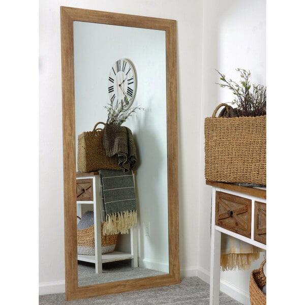 A BrandtWorks blonde barn finish wall mirror in a white room with a basket of plants.