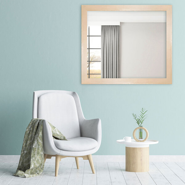 A BrandtWorks natural grain finish mirror on a blue wall above a white chair with a green blanket and a plant.