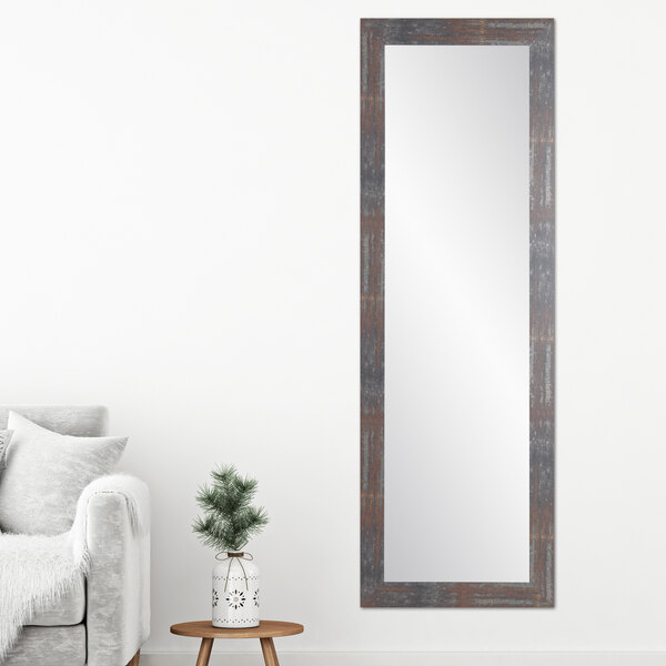 A long BrandtWorks modern rust finish mirror on a wall above a white couch.