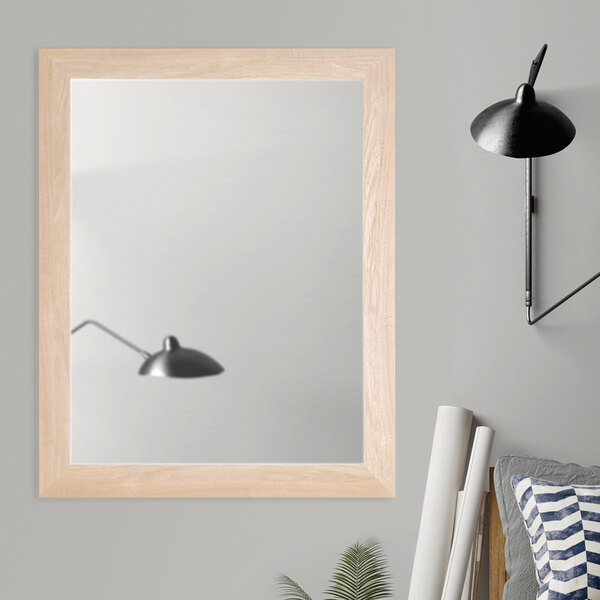 A BrandtWorks natural grain finish mirror on a white wall in a room.
