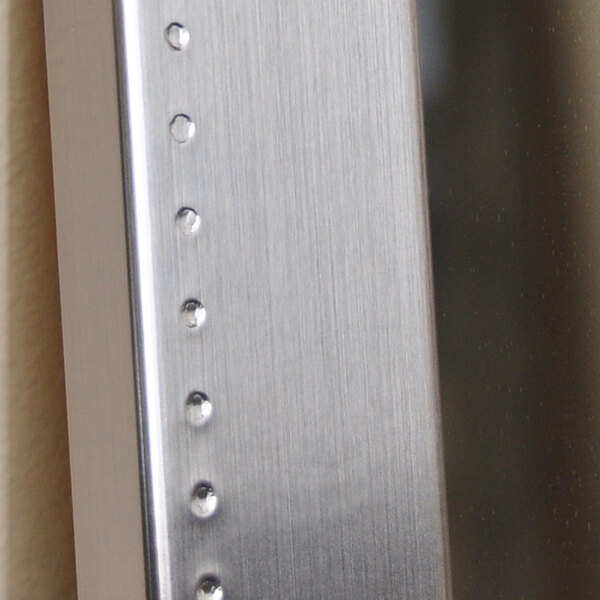 A close-up of a BrandtWorks embossed metal frame with a silver finish.