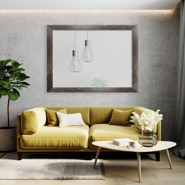 A BrandtWorks rustic brown mirror hanging above a yellow couch with pillows and a picture on the wall.