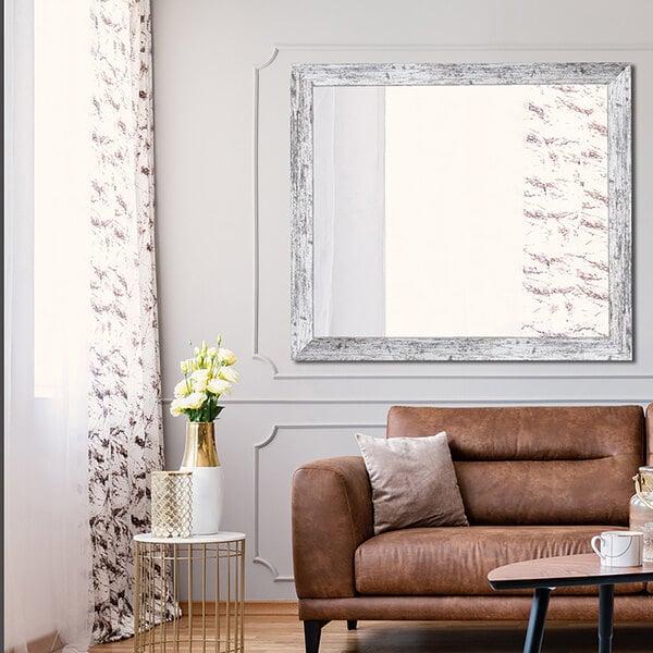 A living room with a brown leather couch and a BrandtWorks American Barn Wall mirror above it.