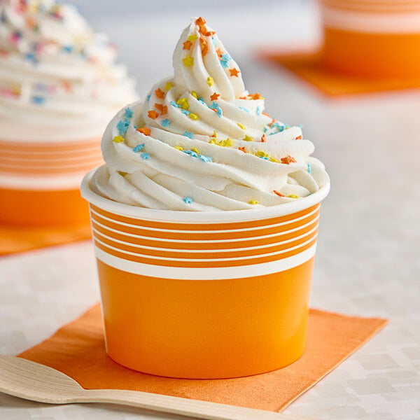 A Choice orange paper frozen yogurt cup filled with ice cream and sprinkles.